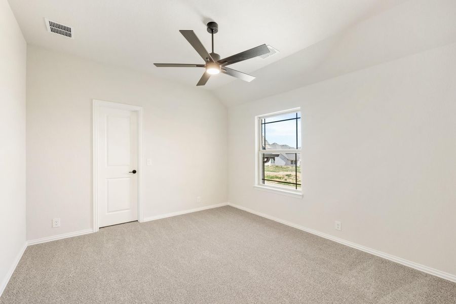 Empty bedroom with vaulted ceiling, ceiling fan, carpet flooring, and a single window