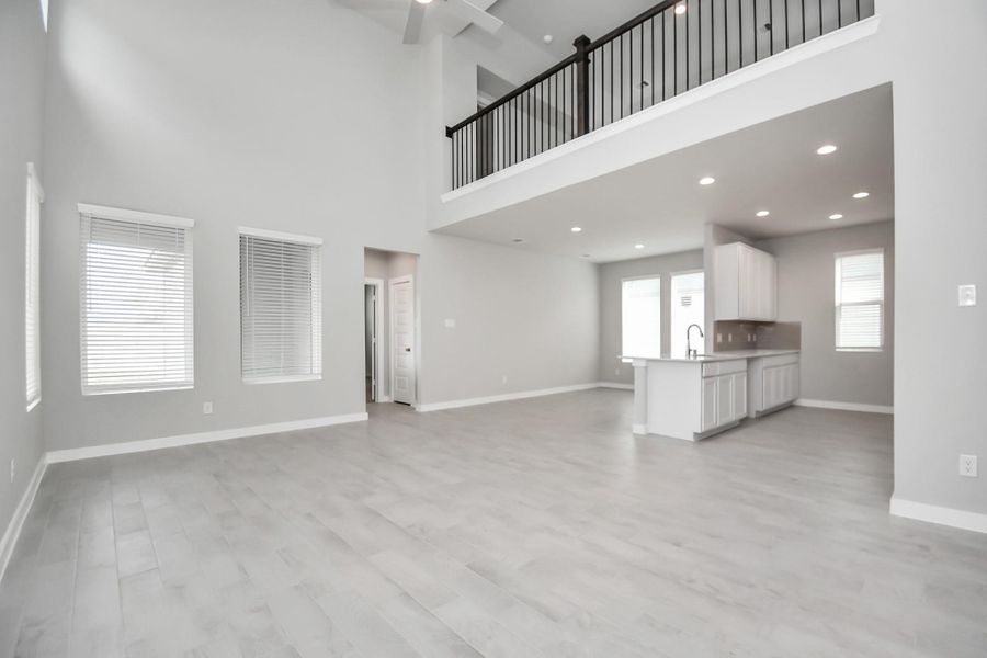 Welcome family and guests to your charming living room! With its high ceilings, recessed lighting, ceiling fan, custom paint, beautiful flooring, and large windows that let in abundant natural light, this room is perfect for gatherings. Sample photo of completed home with similar floor plan. Actual colors and selections may vary.