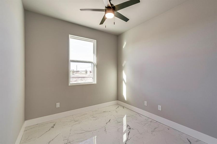 Empty room featuring a ceiling fan, baseboards, and marble finish floor