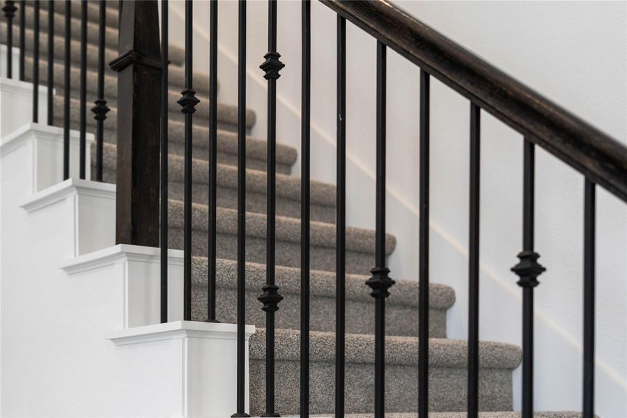 Focus on the quality architectural details of this home, including sleek wrought iron balusters and dark wood handrails.