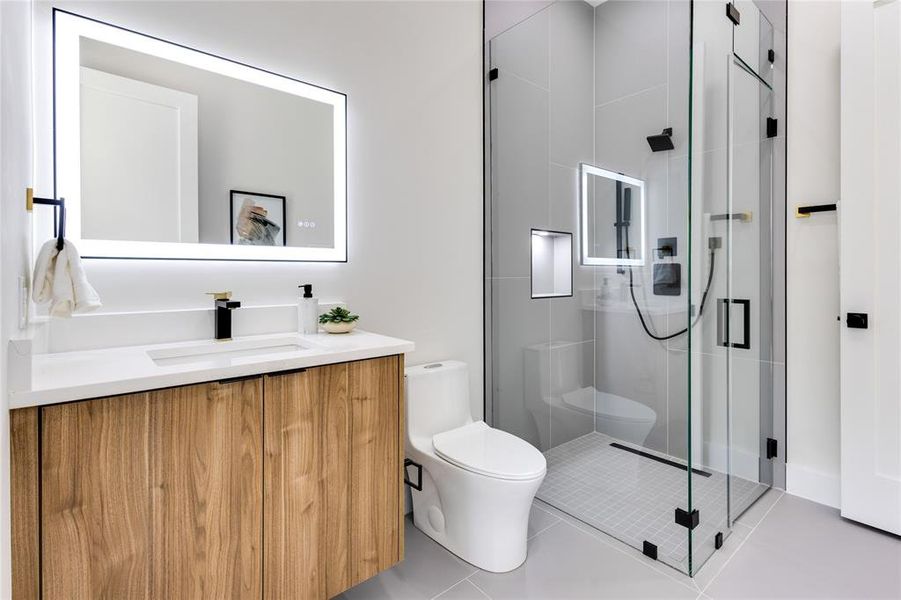 Bathroom featuring toilet, tile patterned floors, vanity, and an enclosed shower