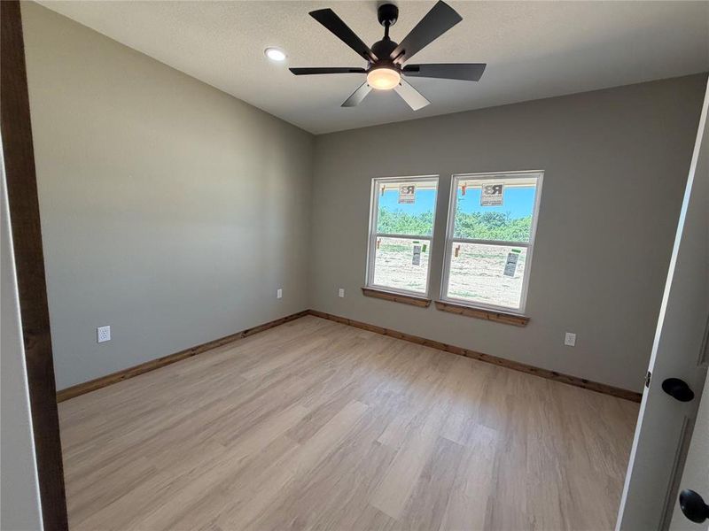 Bright room featuring two large windows, wood-finish flooring, a contemporary ceiling fan with integrated lighting, recessed lighting, and neutral wall tones
