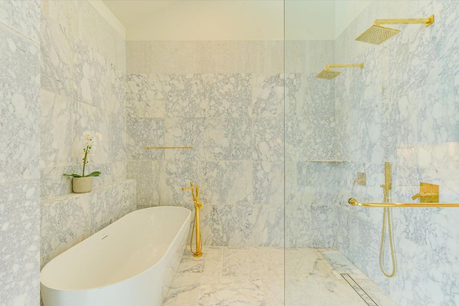 Bathroom featuring a marble finish shower, a freestanding bath, tile walls, and marble finish flooring