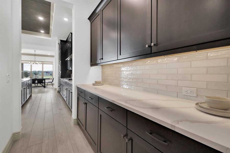 Kitchen with recessed lighting, a chandelier, backsplash, light stone counters, and light wood-style floors