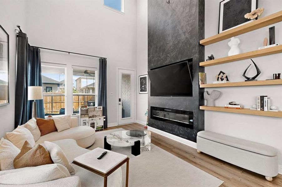 Living area with light wood-type flooring, a large fireplace, plenty of natural light, and a towering ceiling Living area with light wood-type flooring, a large fireplace, plenty of natural light, and a towering ceiling