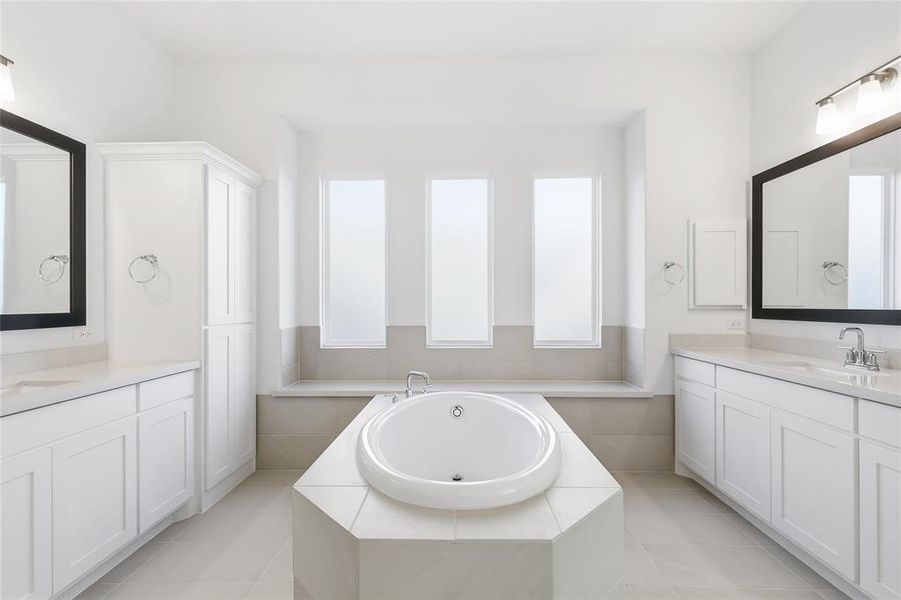 Bathroom with two vanities, a garden tub, and light tile patterned flooring Bathroom with two vanities, a garden tub, and light tile patterned flooring