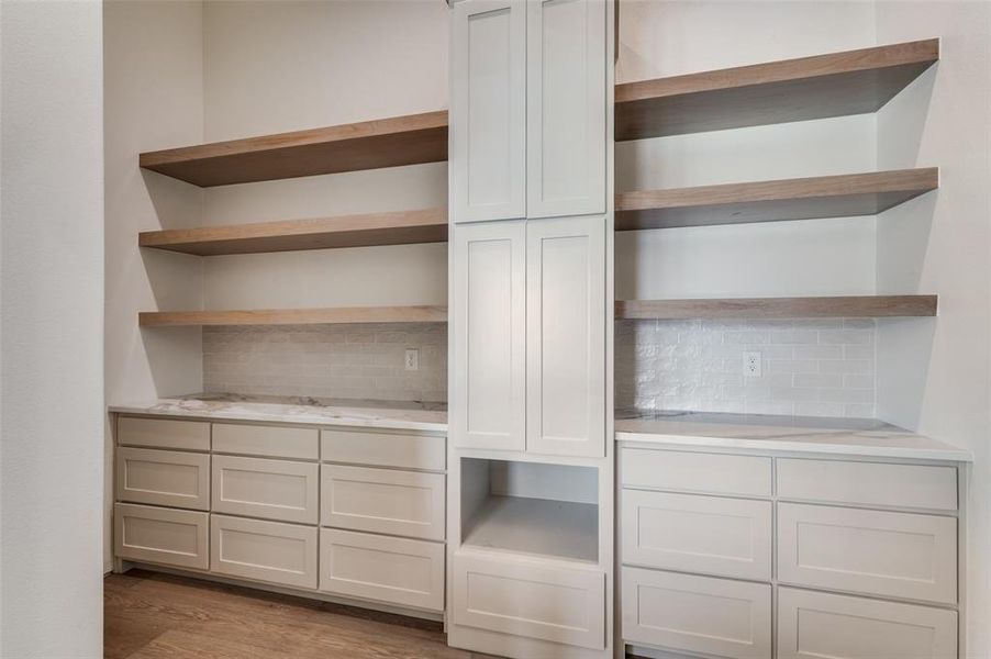 View of walk-in pantry from french doors. Built-ins with white oak floating shelves and quartz countertops. View of walk-in pantry from french doors. Built-ins with white oak floating shelves and quartz countertops.