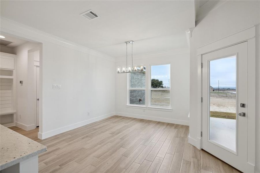 Unfurnished dining area with ornamental molding, light hardwood / wood-style flooring, and a chandelier