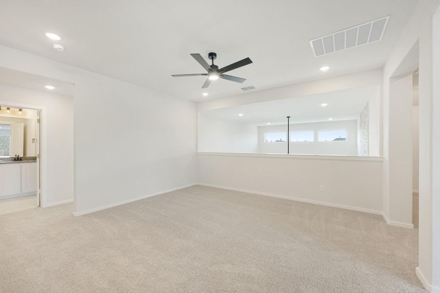 Spacious bedroom with carpet, ceiling fan, recessed lighting, and attached bathroom visible through doorway. Spacious bedroom with carpet, ceiling fan, recessed lighting, and attached bathroom visible through doorway.