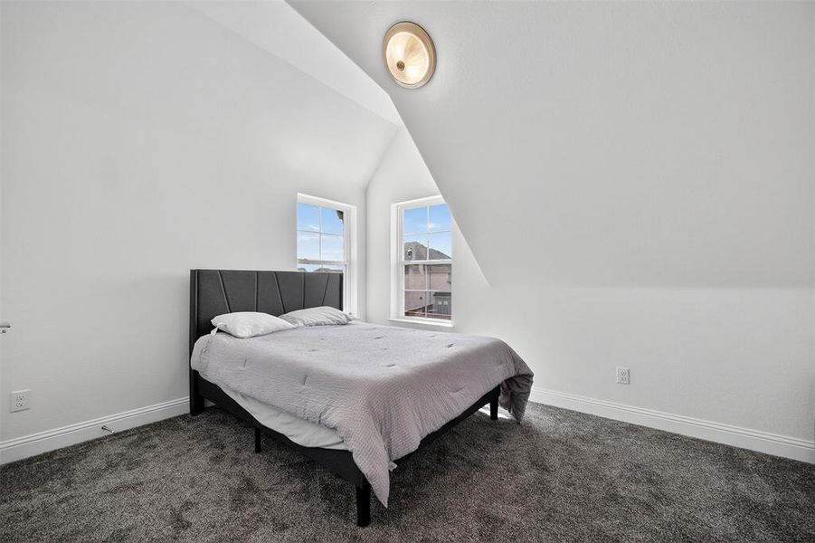 Bedroom featuring dark colored carpet and lofted ceiling Bedroom featuring dark colored carpet and lofted ceiling