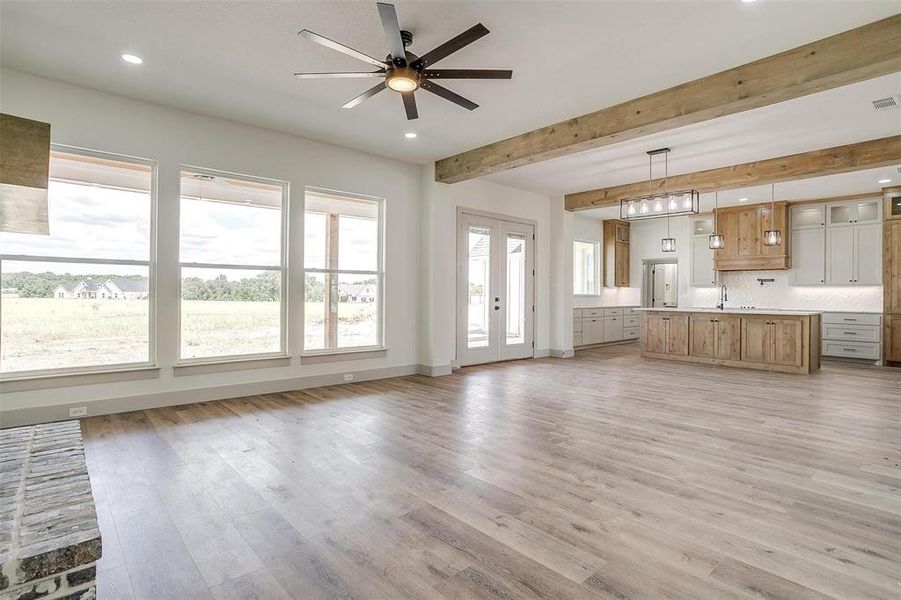 Unfurnished living room featuring light wood-type flooring, a healthy amount of sunlight, sink, and ceiling fan