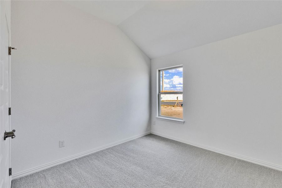 Carpeted spare room with lofted ceiling and baseboards Carpeted spare room with lofted ceiling and baseboards