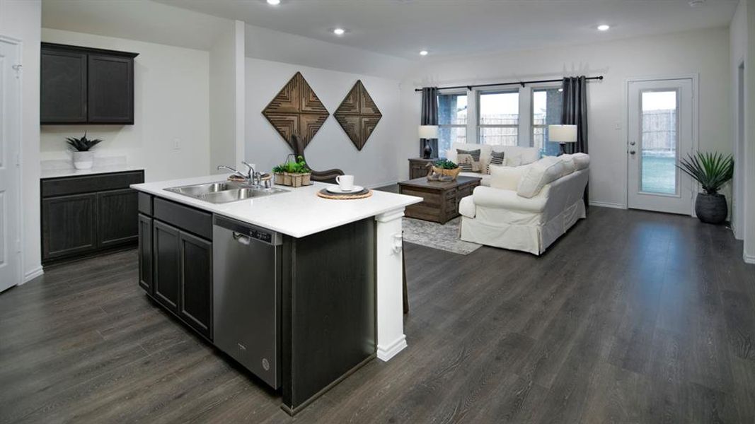 Kitchen with light countertops, open floor plan, stainless steel dishwasher, recessed lighting, and a kitchen island with sink
