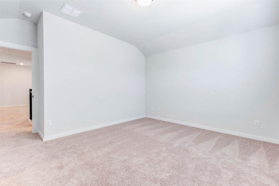 Another upstairs bedroom offers generous dimensions and soft carpet underfoot, creating a restful retreat. The door leads to a walk-in closet while a nearby hall and game room make this layout ideal for family or guests.