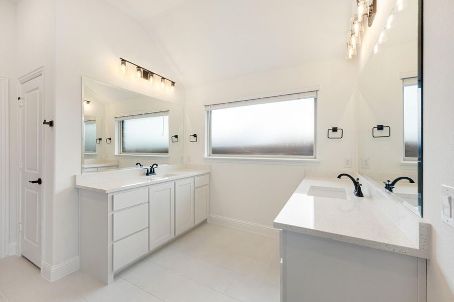 Bathroom with dual vanities, white quartz countertops, black fixtures, and large mirrors with vanity lighting Bathroom with dual vanities, white quartz countertops, black fixtures, and large mirrors with vanity lighting