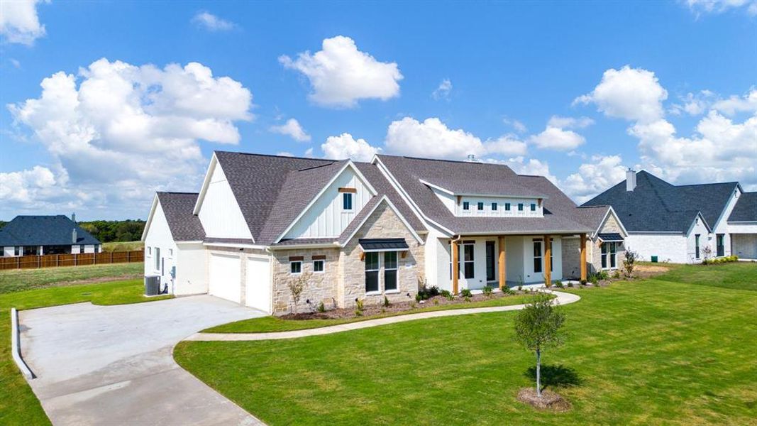 View of front facade featuring cooling unit, a garage, and a front lawn