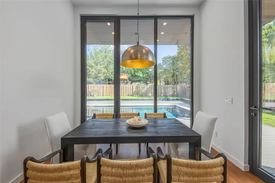 A refined dining space with hardwood floors and panoramic views of the inviting pool area.