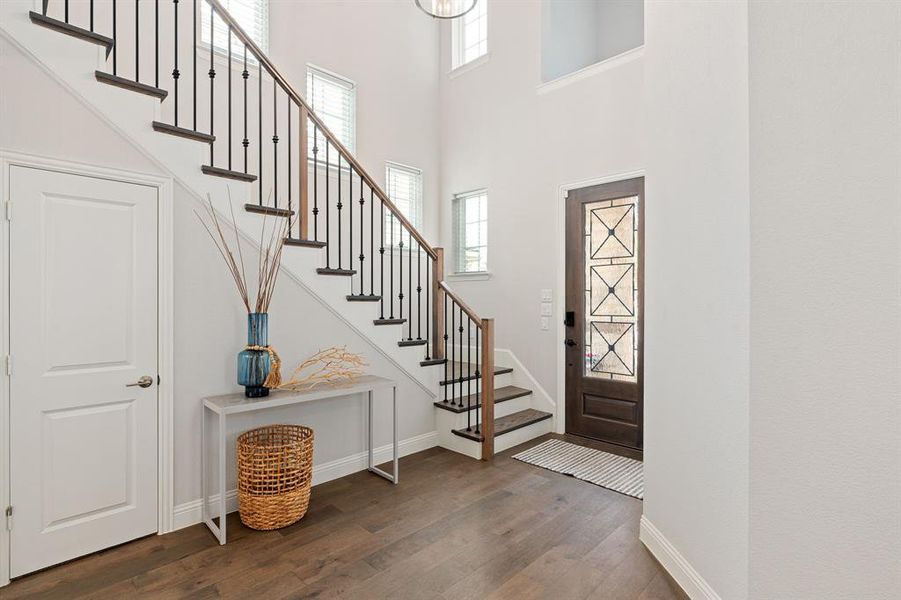 Entryway featuring a towering ceiling, plenty of natural light, and beautiful wood floors