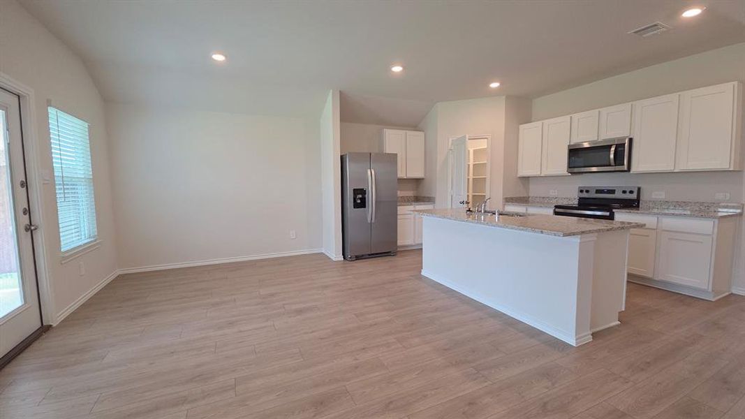 Open-concept living area featuring wood-finish flooring, recessed lighting, and a kitchen island with a stone countertop