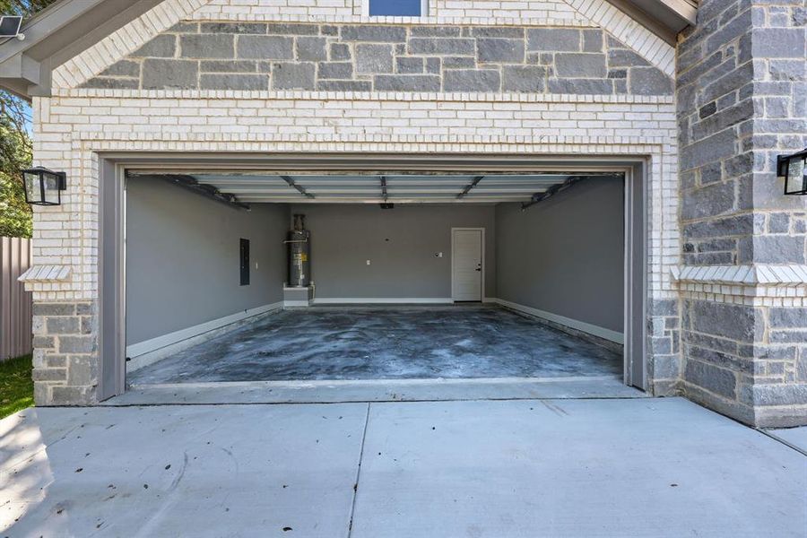 Garage featuring driveway, water heater, and electric panel Garage featuring driveway, water heater, and electric panel