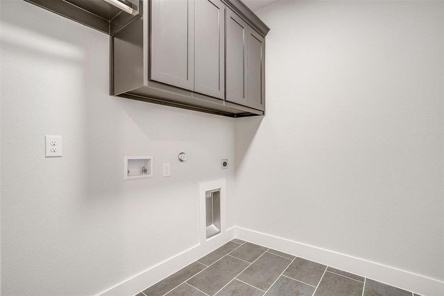 Clothes washing area featuring cabinets, gas dryer hookup, hookup for a washing machine, dark tile patterned flooring, and hookup for an electric dryer