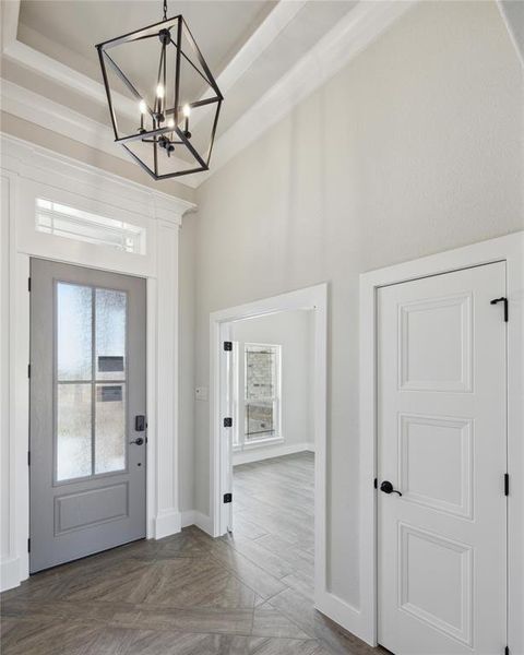 Entryway with a chandelier, dark parquet floors, and a tray ceiling