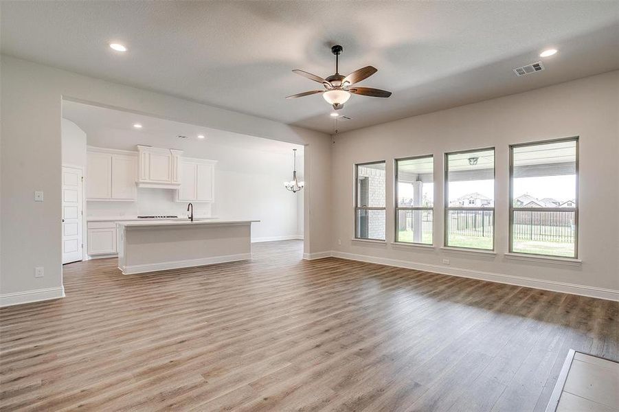 Unfurnished living room featuring sink, ceiling fan with notable chandelier, and light hardwood / wood-style flooring