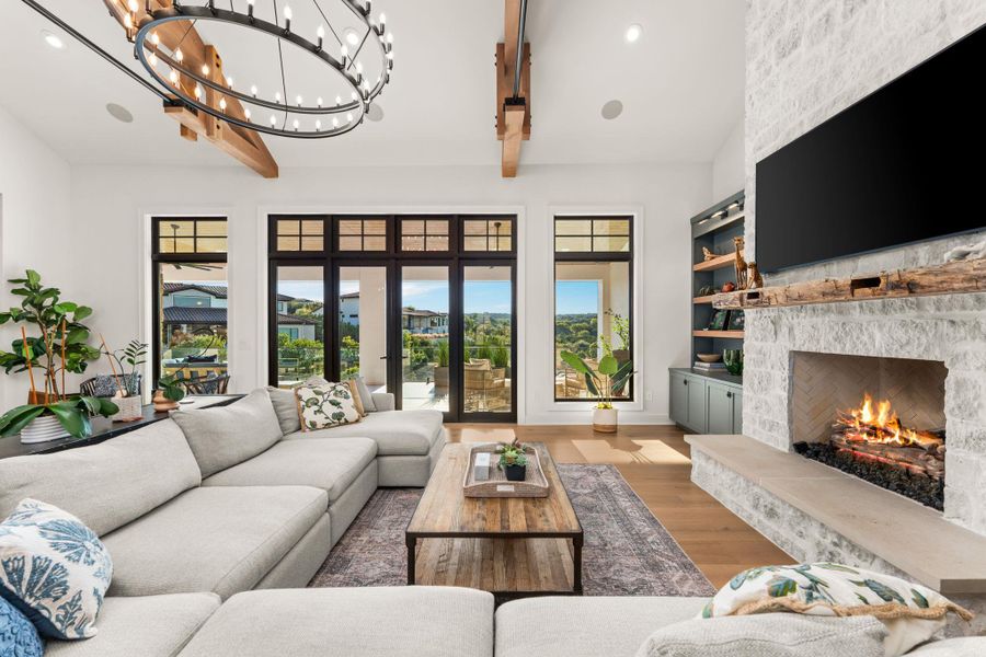 Living area with wood finished floors, beam ceiling, recessed lighting, a fireplace, and a chandelier Living area with wood finished floors, beam ceiling, recessed lighting, a fireplace, and a chandelier
