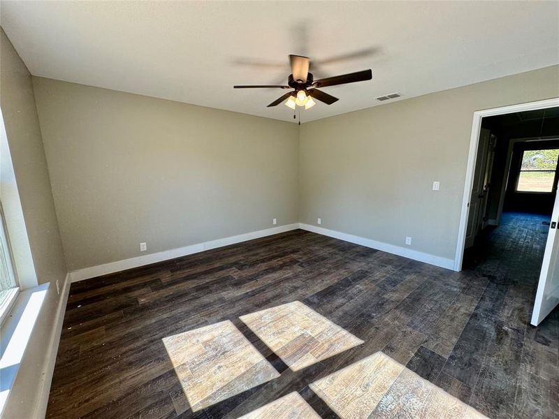 Unfurnished room featuring dark wood-type flooring and ceiling fan