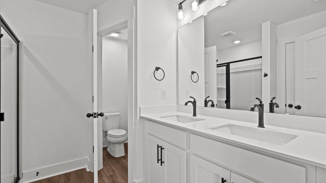 Accomplished design shines in this primary bath with dual vanity and a sleek walk-in shower