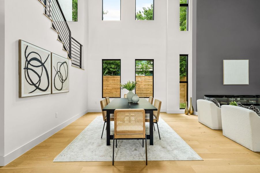 A spacious dining area with soaring ceilings and light hardwood floors creates an inviting atmosphere for entertaining. A spacious dining area with soaring ceilings and light hardwood floors creates an inviting atmosphere for entertaining.