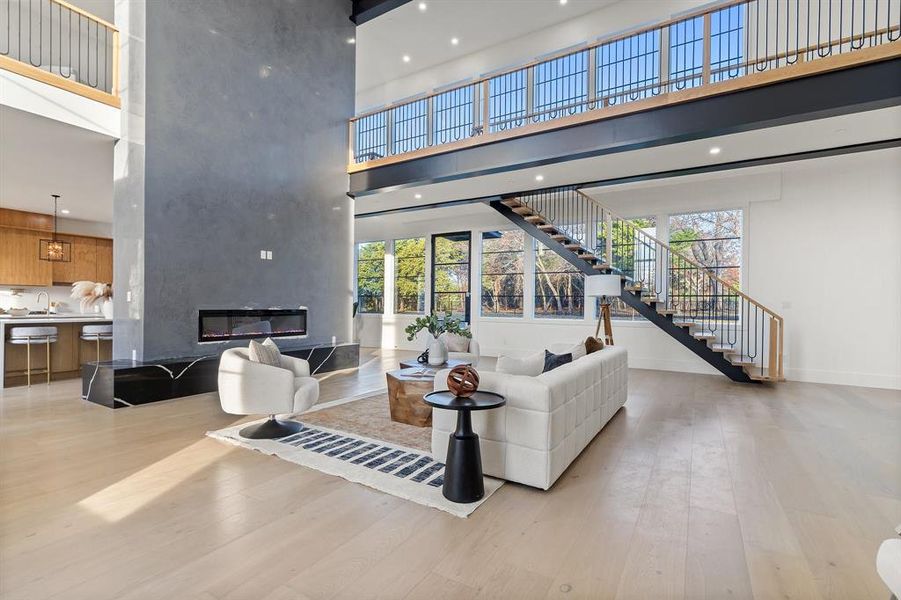 Living room with a fireplace, a high ceiling, light hardwood / wood-style flooring, and sink