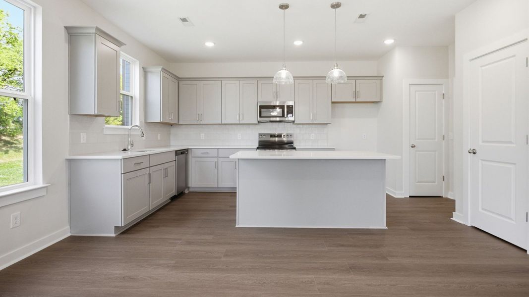 Kitchen with light cabinetry, quartz countertops, tile backsplash, and pantry Kitchen with light cabinetry, quartz countertops, tile backsplash, and pantry