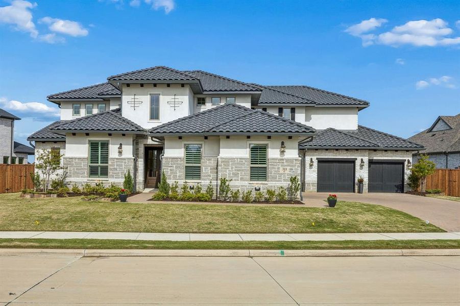 Mediterranean / spanish-style house with stone siding, driveway, a garage, stucco siding, and a tile roof