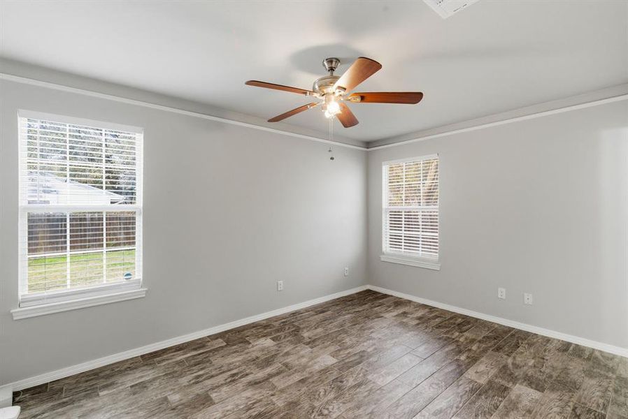 Empty room with wood finished floors, crown molding, and ceiling fan Empty room with wood finished floors, crown molding, and ceiling fan