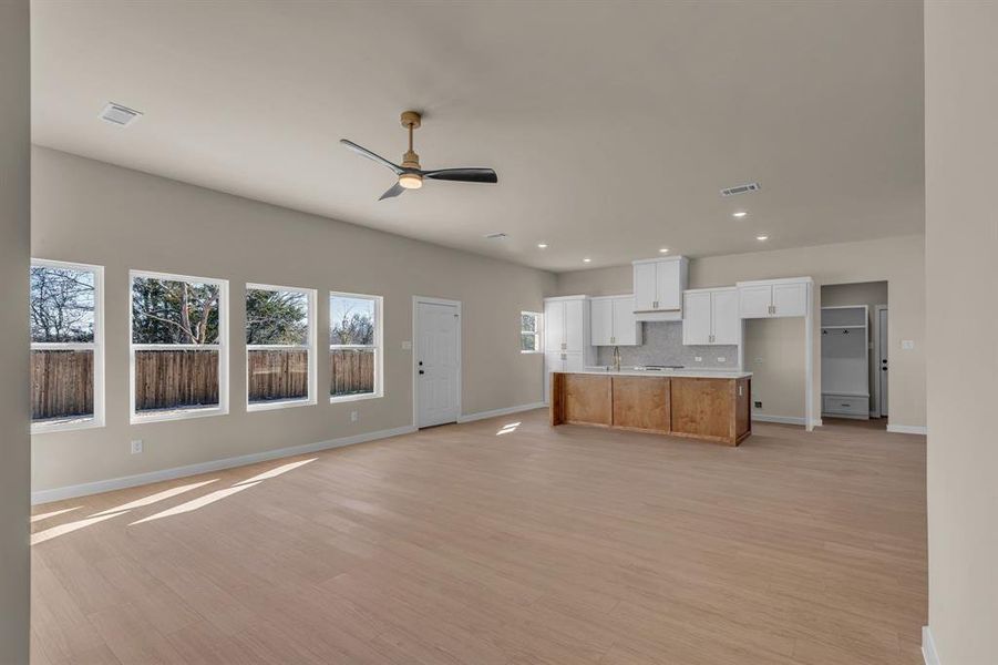 Unfurnished living room with ceiling fan, sink, and light wood-type flooring