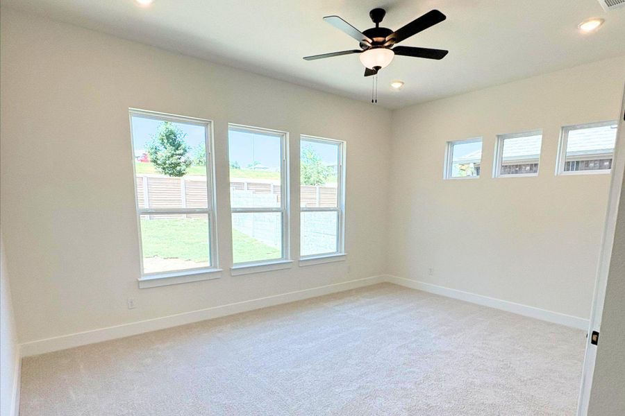 Generous windows frame neighborhood views in this light-filled room with high ceilings and carpeted flooring. Generous windows frame neighborhood views in this light-filled room with high ceilings and carpeted flooring.