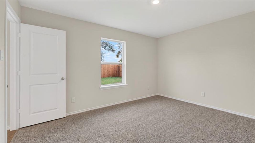 Neutral-toned interior room featuring light gray walls, gray carpet flooring, and a white two-panel door