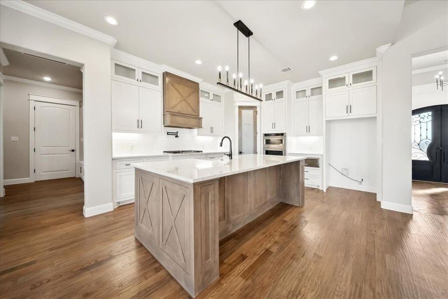 Kitchen featuring a kitchen island with sink, dark hardwood / wood-style floors, and white cabinets