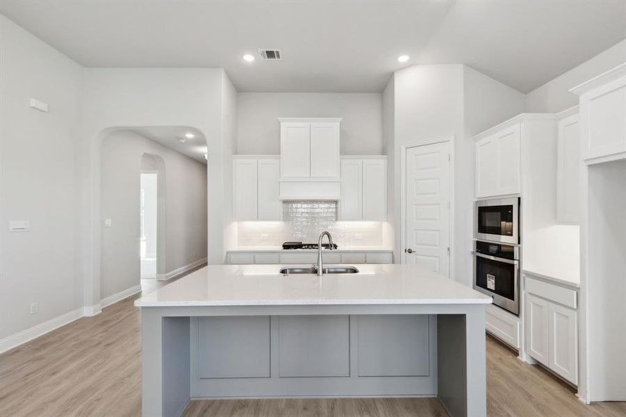 Kitchen featuring white cabinets, stainless steel appliances, a kitchen island with sink, and sink