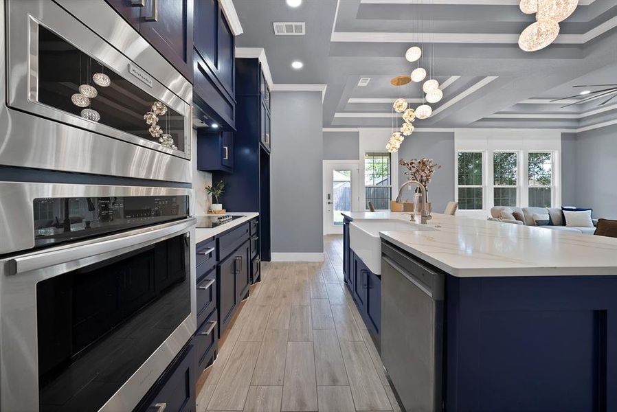 Gourmet kitchen with built-in stainless steel appliances, navy cabinetry, white countertops, and wood-finish flooring