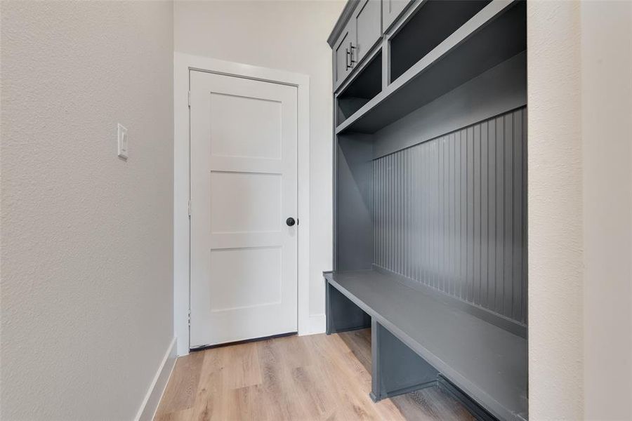 Built-in mudroom bench with beadboard paneling, open shelving, and upper storage cabinetry