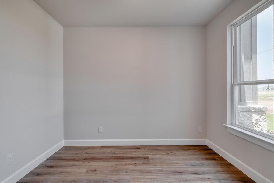 Unfurnished room featuring light wood finished floors and baseboards