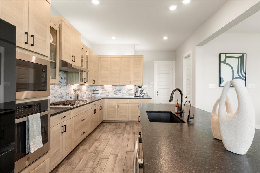 A contemporary kitchen features light wood cabinetry, sleek dark countertops, and modern stainless steel appliances. A contemporary kitchen features light wood cabinetry, sleek dark countertops, and modern stainless steel appliances.