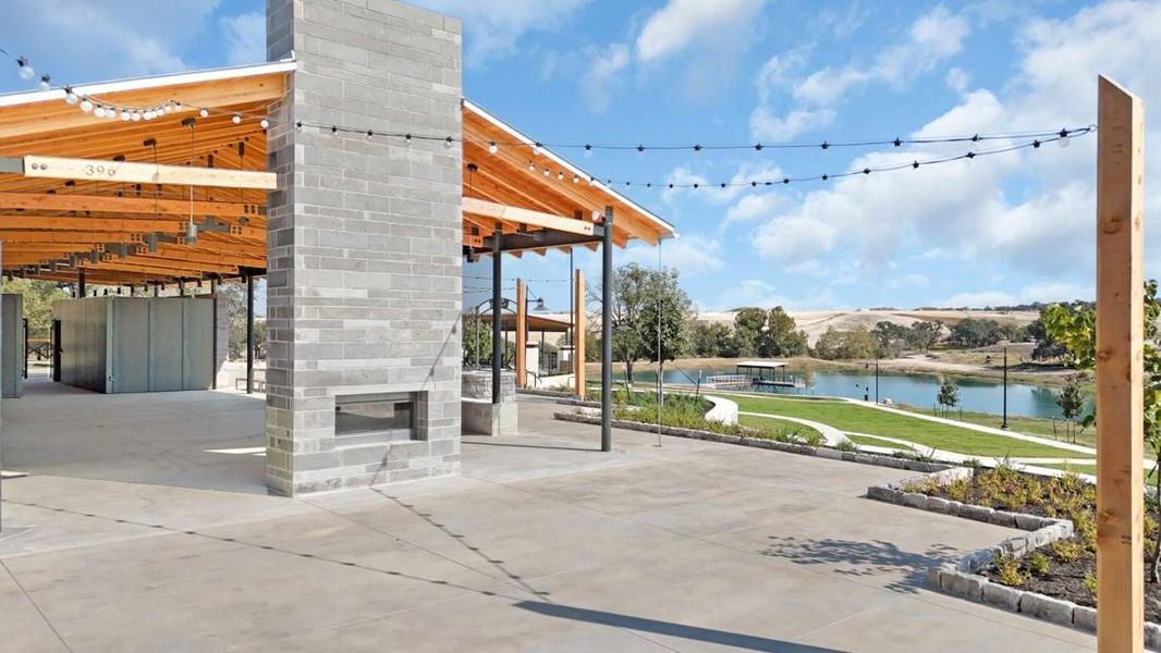 View of patio featuring a water view, a glass covered fireplace, and a pergola