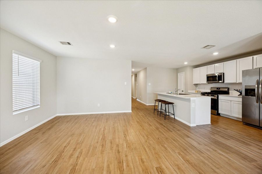 Bright, open-concept living area with vinyl flooring, modern kitchen appliances, and ample natural light. Perfect for entertaining.