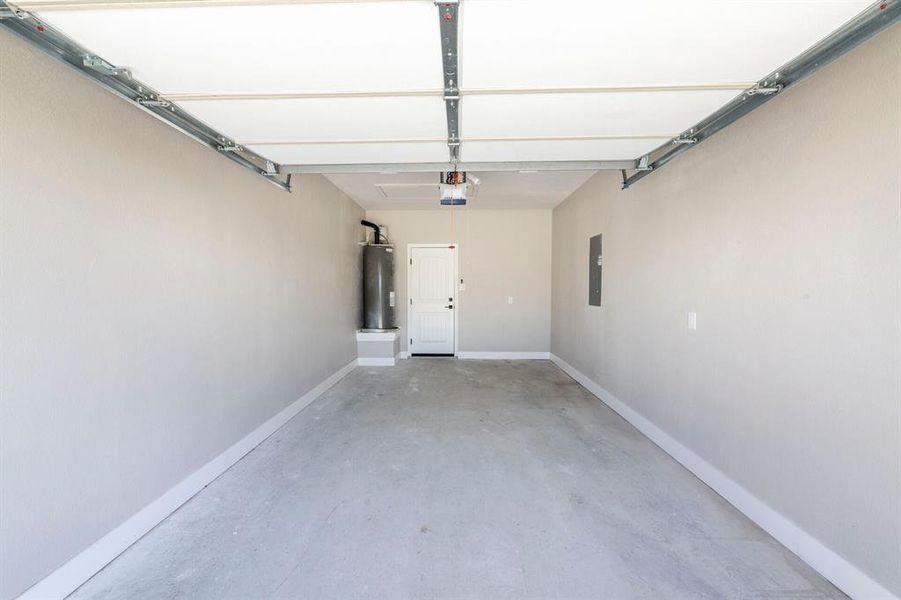Garage featuring electric water heater, electric panel, and a garage door opener Garage featuring electric water heater, electric panel, and a garage door opener
