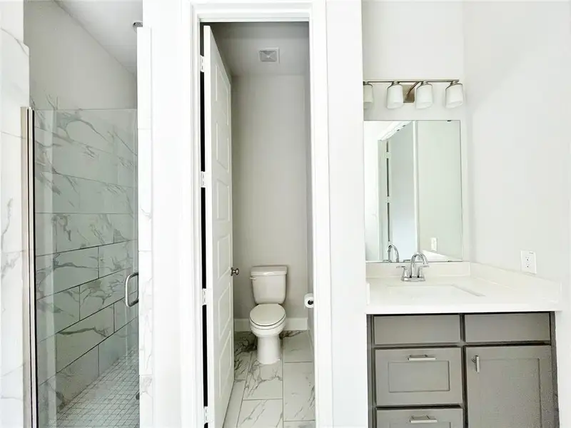Bathroom featuring a marble finish shower, light marble finish floors, and vanity Bathroom featuring a marble finish shower, light marble finish floors, and vanity