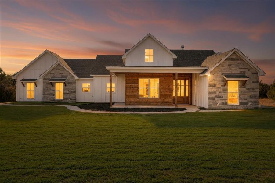 Modern inspired farmhouse featuring stone siding, board and batten siding, and a lawn