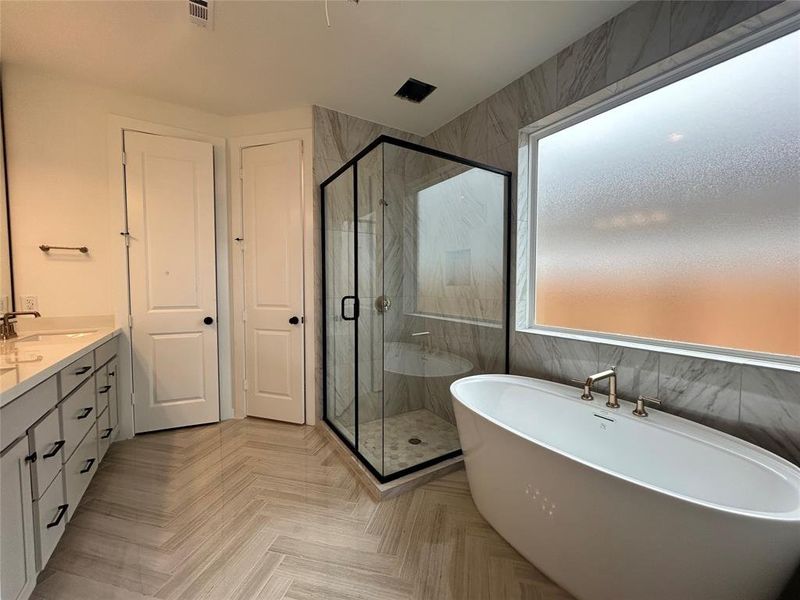 The main bathroom features a luxurious design with dual vanities, a soaking tub, and a spacious walk-in shower. Its modern finishes and thoughtful layout create a spa-like retreat for relaxation and convenience.